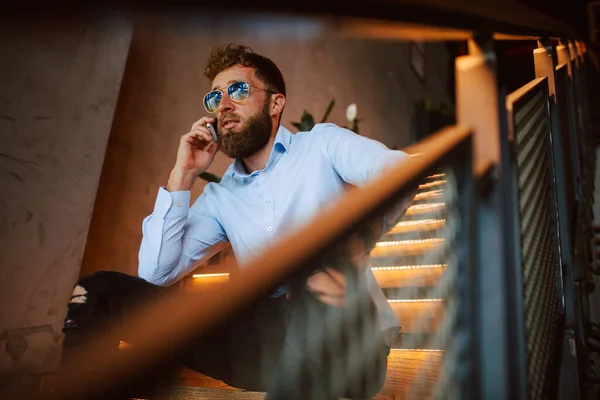 喫茶店の階段にサングラスをかけた若い白人男性が電話で話している レストランでハンサムなビジネスマン — ストック写真