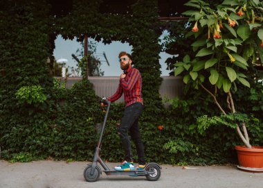 Şehirde elektrikli scooter kullanan yakışıklı bir adam.