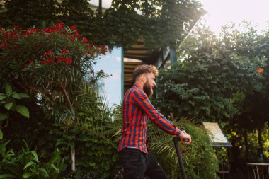 Şehirde elektrikli scooter kullanan yakışıklı bir adam.