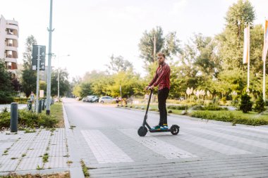 Şehirde elektrikli scooter kullanan yakışıklı bir adam.