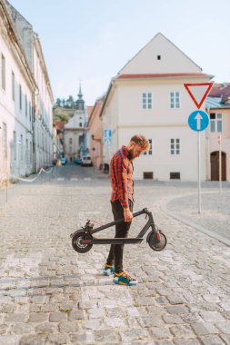 Şehirde elektrikli scooter kullanan yakışıklı bir adam.