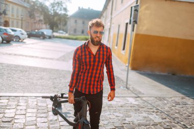 Şehirde elektrikli scooter kullanan yakışıklı bir adam.
