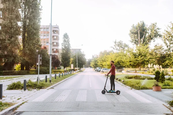 Şehirde elektrikli scooter kullanan yakışıklı bir adam.