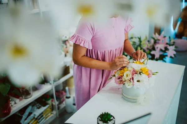 一个穿着粉红衣服的高加索女人在花店的桌子上摆弄一束花的手 做一束花 — 图库照片