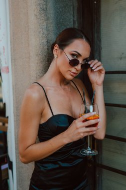 Güneş gözlüklü ve elinde kokteyl olan güzel bir kadının portresi.