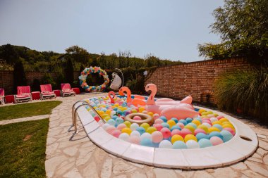 Havuz balonları ve pembe flamingolarla çok güzel dekore edilmiş bir bahçe. Bir yaz partisi için bahçe süslemesi