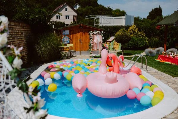 Havuz balonları ve pembe flamingolarla çok güzel dekore edilmiş bir bahçe. Bir yaz partisi için bahçe süslemesi