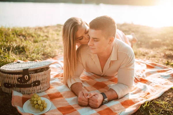 川のピクニックで毛布の上に横たわる白人男性とブロンドの女性の肖像画 ロマンチックな幸せな愛のカップルで夕日 — ストック写真