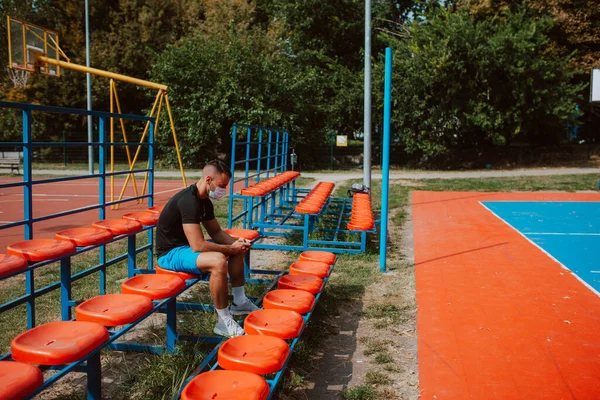 Mladý Svalnatý Bělošský Atlet Obličejovou Maskou Sedící Tribuně Fotbalového Hřiště — Stock fotografie