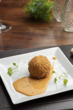 Arancini risotto ve sıcak domates sosu üzerine doldurulmuş mozzarella ile bulanık arka planı olan bir tabağa konur.