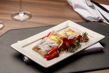 Kremalı puf böreği, çilek ve üstüne de çiçek ve biberiyeyle süslenmiş şeker.