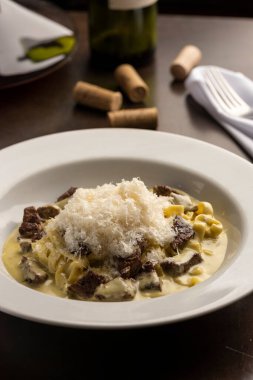 et ve peynir gnocchi makarna sığır filetosu ve beyaz kremalı sos ahşap masa üzerinde şarap, bardak, mantar ve peçete