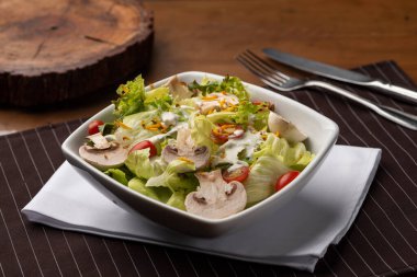 Ahşap ve çatalla kaplı bulanık bir geçmişi olan mantarlı domates salatası.