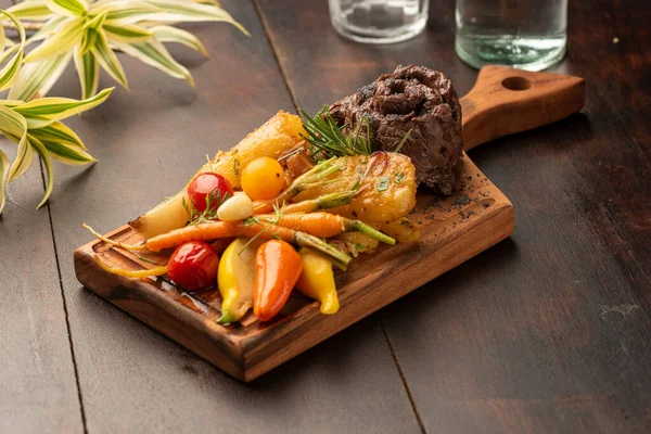 flank flat iron skirt steak with vegetables on a wood board and blurred background
