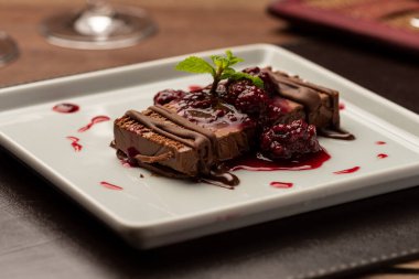 Beyaz tabakta ahududu şurubuyla terrine çikolatalı kek.