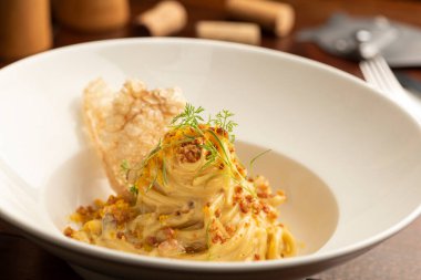 Beyaz tabakta, şarap mantarlı, bulanık arka planı olan Carbonara makarnası.