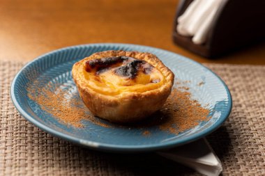 Portekiz kremalı turtası - Pastel de Belem ve Pastel de Nata mavi seramik ve ahşap masa üzerinde