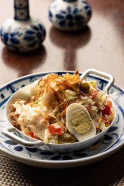 Pirinçli morina balığı Bacalhau, soğan yumurtası zeytinyağı - portuguez geleneksel yemeği ahşap masa paspası ve bulanık arka plan