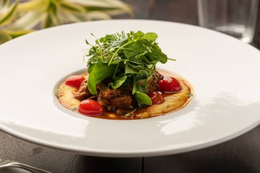 Mısır unundan yapılmış kremalı polenta soslu domates ve bulanık arkaplanlı salata.