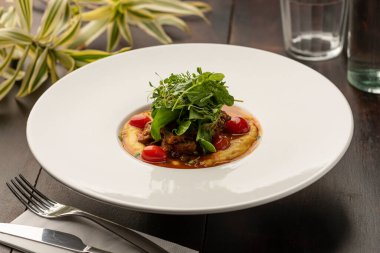 Mısır unundan yapılmış kremalı polenta soslu domates ve bulanık arkaplanlı salata.