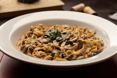 Ahşap masa üzerinde mantar funghi kremalı makarna tagliatelle şarap, cam mantar.