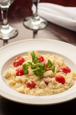 Vişneli domates peynirli risotto ve fesleğen ahşap masa üzerinde şarap bardakları ve peçete