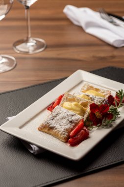 Kremalı puf böreği, çilek ve üstüne de çiçek ve biberiyeyle süslenmiş şeker.