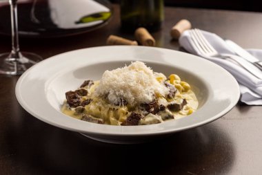 et ve peynir gnocchi makarna sığır filetosu ve beyaz kremalı sos ahşap masa üzerinde şarap, bardak, mantar ve peçete