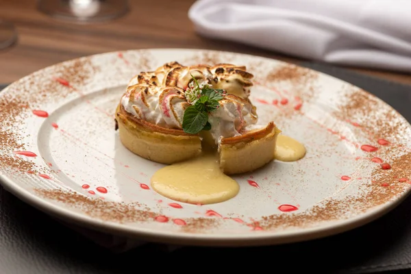 Lemon tart pie with whipped cream desert on a white decorated plate wooden table and blurred background