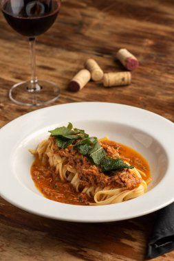 Beyaz tabakta kırmızı öğütülmüş biftekli makarna ve bulanık arka plan..