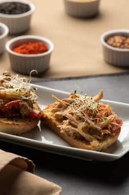 Tabakta bruschetta ve arka planda baharatlar ve peçeteyle deri minder.