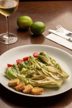 Salata, salatanın yarısı salata soslu şarap kadehi ve limonlar ahşap masada.