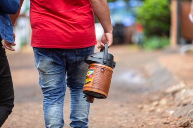 man walking holding a thermal bottle used to drink traditional chimarrao terere and guampa clipart