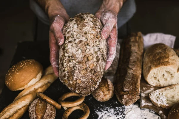 Baker hombre sosteniendo un pan orgánico rústico en sus manos — Foto de Stock