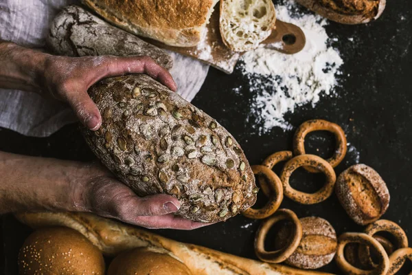 Baker homme tenant dans ses mains un pain bio rustique — Photo
