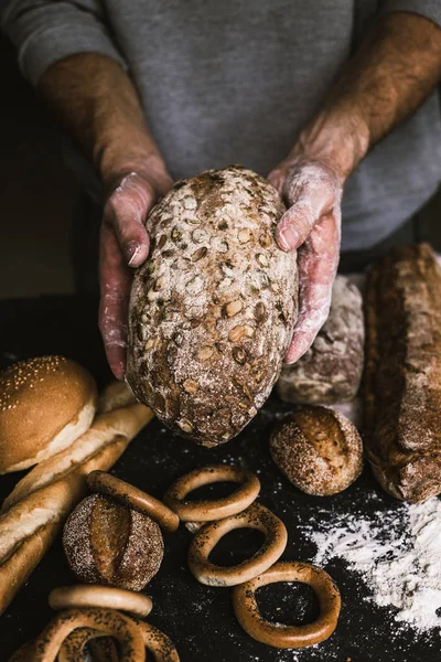 Baker άνθρωπος που κρατά ένα ρουστίκ οργανικά καρβέλι ψωμί στα χέρια του — Φωτογραφία Αρχείου