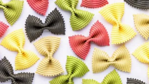 Gekleurde vlinderdas pasta. Close-up meerdere farfalle geïsoleerd op witte achtergrond. — Stockvideo