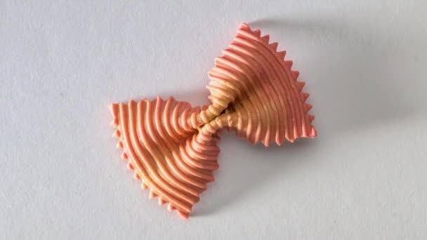 Ζυμαρικά με παπιγιόν. Κοντινό πλάνο ενιαίο πορτοκαλί farfalle σε λευκό φόντο. — Αρχείο Βίντεο