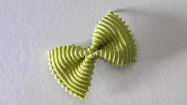 Kolorowy makaron z muszką. zbliżenie pojedynczy zielony farfalle na szarym tle. — Wideo stockowe