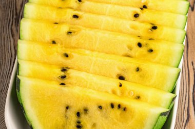 Tabakta taze sarı karpuz dilimleri.