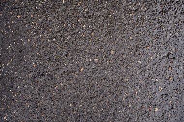 Siyah ıslak asfalt, çakıl taşlarını da kapsıyor.