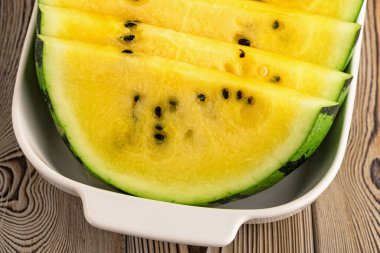 Tabakta taze sarı karpuz dilimleri.