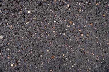 Siyah ıslak asfalt, çakıl taşlarını da kapsıyor.