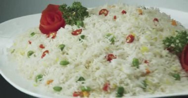 Bezelye, yeşil fasulye, havuç, maydanoz ve gül şeklinde domateslerle süslenmiş 4k pişmiş beyaz pirinç videosu. Bu tabağı döndürün ve çeşitli şekillendirilmiş yiyecek perspektifleri oluşturun.