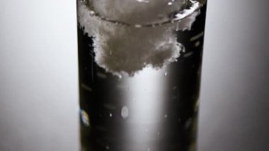 Bardakta soda köpüğü, beyaz arka planda. Yavaş çekim. Güzel görünümlü soda, köpük ve su damlacıkları.