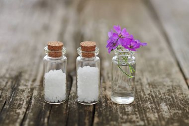 Küçük cam şişe ve küçük pembe çiçekler Homeopatik granül.