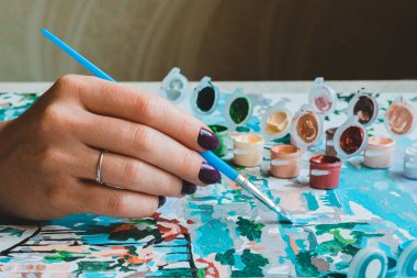 Sanatçı kadının elleri, salgın sırasında boş zamanlarında resim yapıyor. Hobi olarak. 