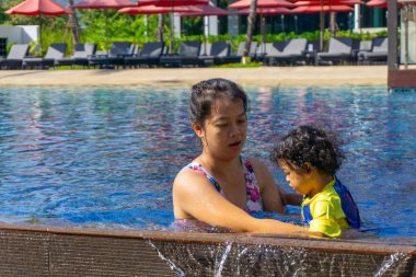 Asyalı çocuk çocuk ile anne bir yüzme havuzunda yüzme öğrenmek.