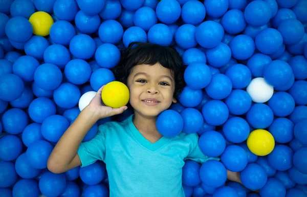 Un piccolo ragazzo asiatico sta giocando con un sacco di palla blu e gialla — Foto Stock