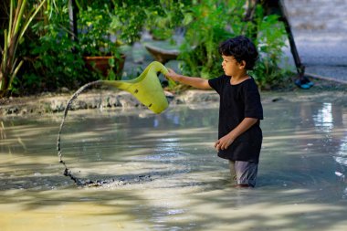 Asyalı çocuk inşa edilmiş bir çamur çukuru içinde eğlenceli bir yerde çamur ile oynuyor